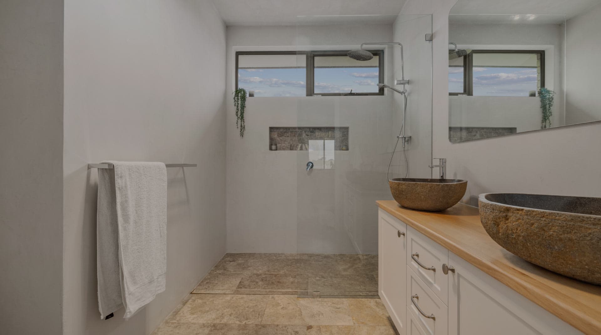 Bathroom renovation with light stone tiles and glass shower