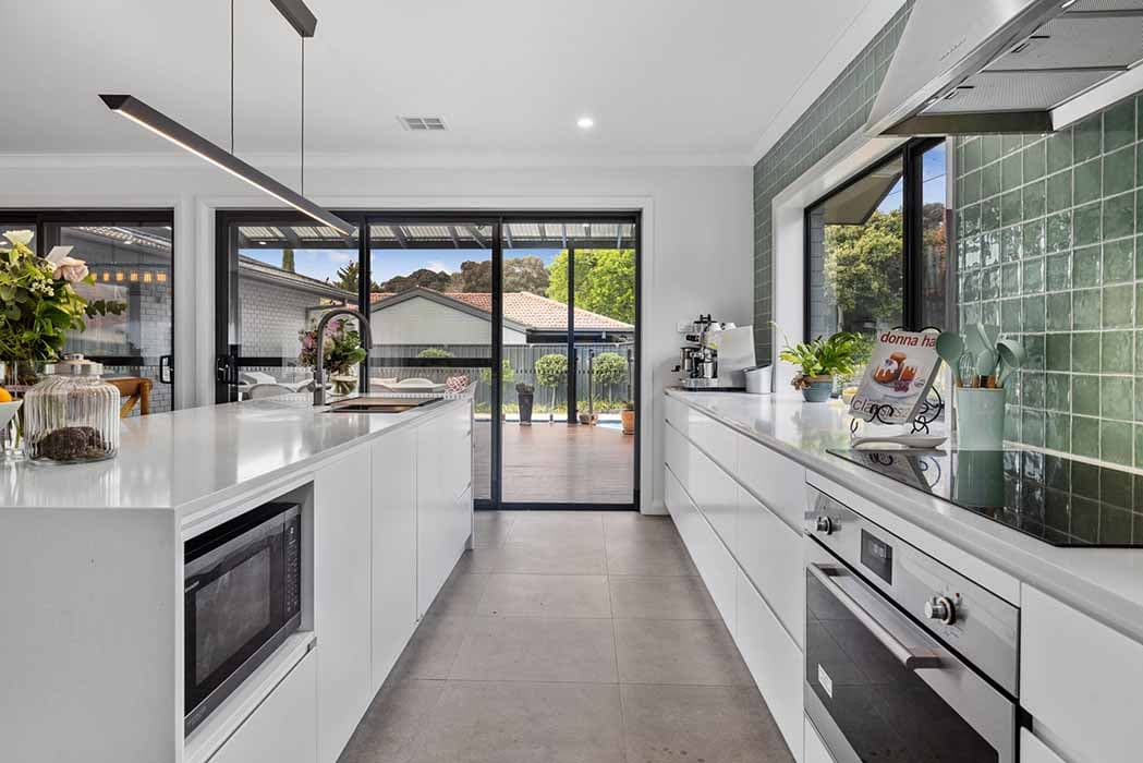 Modern kitchen renovation in Canberra, Australia with sleek design and green tile backsplash.