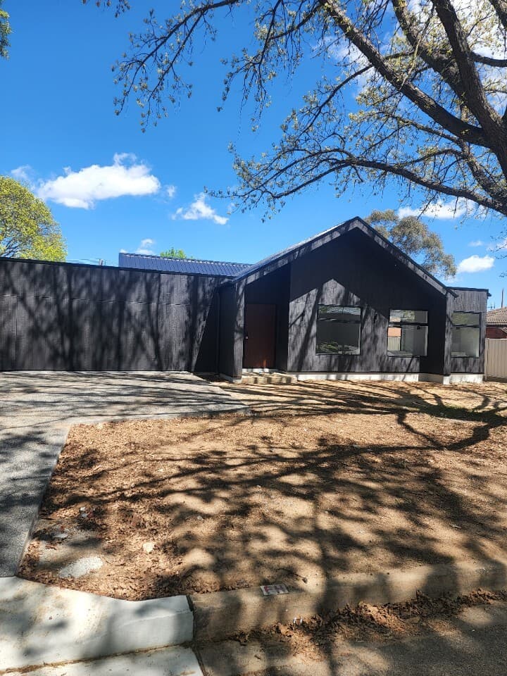 Modern new build in Canberra, Australia with dark cladding and minimalist landscape.